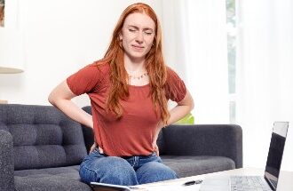 Woman Suffering Back Pain Sitting On The Couch At Home Stock Photo 385x215.jpg