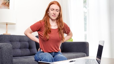 Woman Suffering Back Pain Sitting On The Couch At Home Stock Photo 385x215.jpg